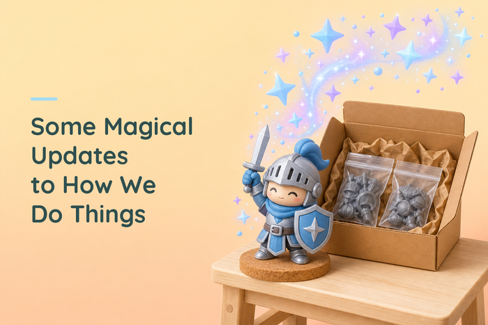 Painted blue and silver chibi knight on a cork disc on a wooden workbench beside an open kraft shipping box holding two bags of grey resin parts, with a large swirl of blue and lavender four-point stars rising to the right