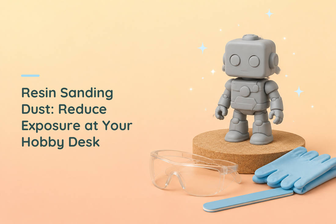 Grey resin robot beside safety glasses, folded blue gloves and a sanding stick on a tidy hobby bench