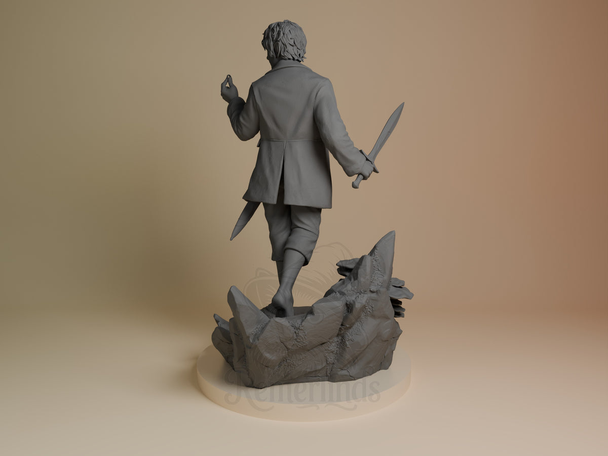 Rear view shows unpainted Bilbo Baggins resin figure from Lord of the Rings walking with a sword on a rocky base.