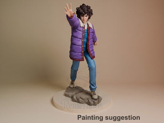 Eleven resin figure in purple jacket and blue shirt, posed with hand raised, standing on rocky base. Painted collectible from Stranger Things.