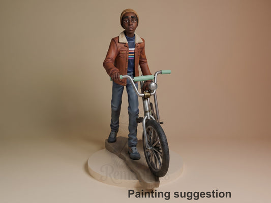 Lucas from Stranger Things resin figure standing with bicycle, wearing brown jacket and beanie, painted in detail on cream base.