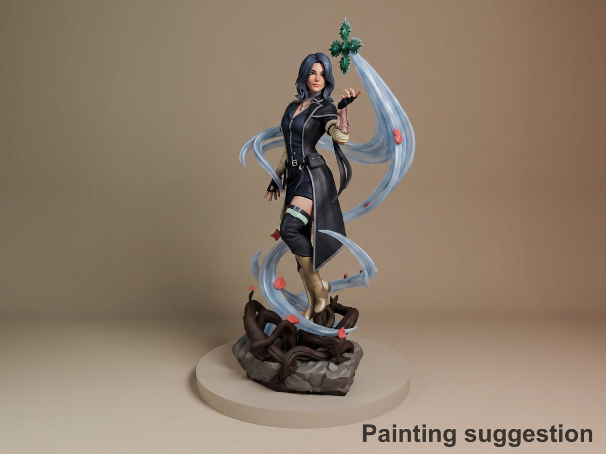 Lune from Expedition 33 resin figure posed on rocky base, blue hair, black outfit, holding ornate green cross, flowing blue ribbons, fully painted.