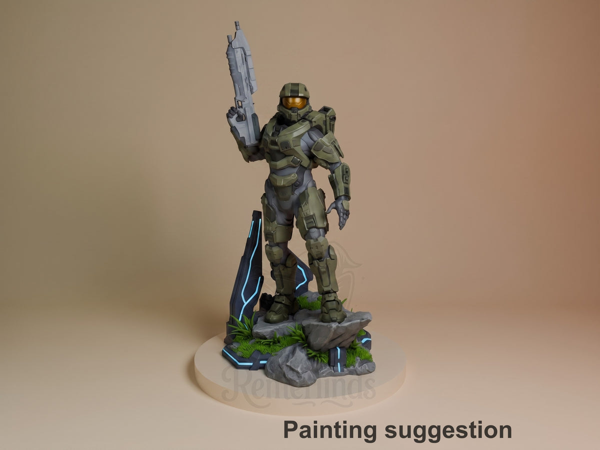 Master Chief resin figure standing on rocky base with blue accents, holding rifle raised, painted in olive and gray armor with gold visor, grass details on base.