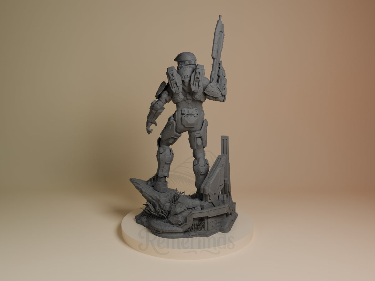 Master Chief resin figure in gray primer, posed standing with rifle raised, on detailed base with rocky terrain, viewed from left side angle.