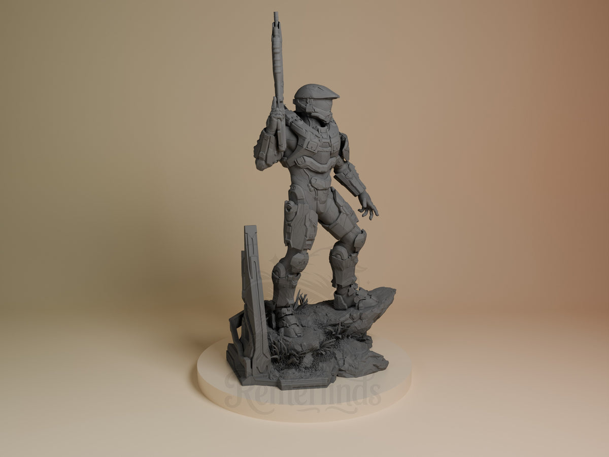 Master Chief resin figure standing right profile on rocky base, holding rifle over shoulder, unpainted gray finish, detailed armor and helmet visible.