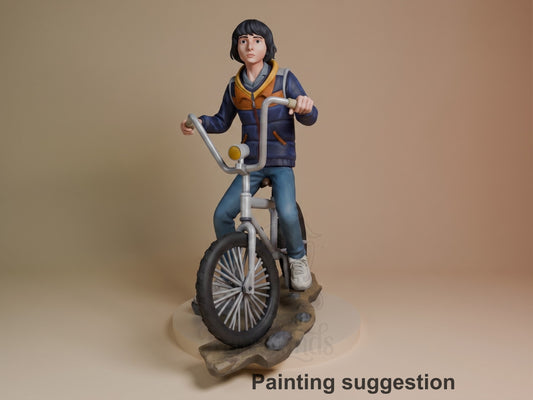 Mike Wheeler resin figure on bicycle, painted navy jacket and jeans, shown from front-left angle on wooden base, labeled painting suggestion.