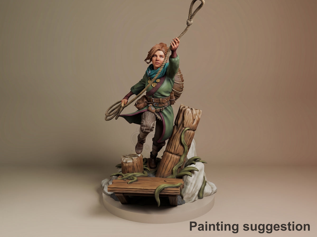 Zoe from Split Fiction resin figure painted in green tunic and brown armor, wielding a rope lasso, posed on wooden base with vines and rocks.