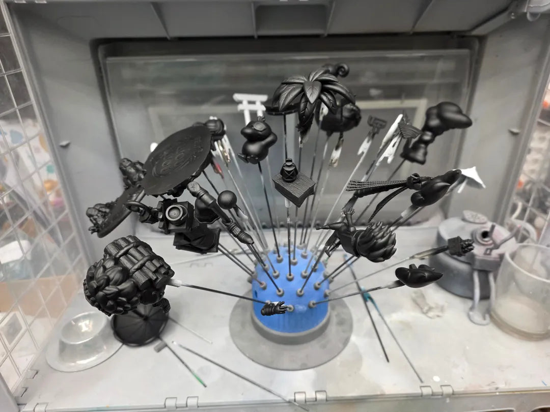 Gold finish chibi resin kit parts in black primer mounted at the Remerlinds airbrushing station